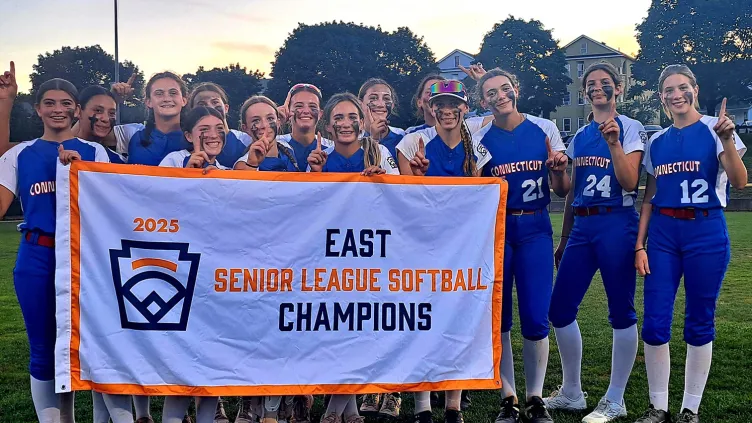 Large group of girls gathered together, smiling, while holding a banner that reads "2025, East Champions Senior League Softball"