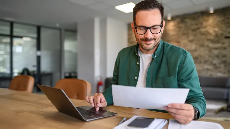 Man auditing financial document and report over computer at his workplace
