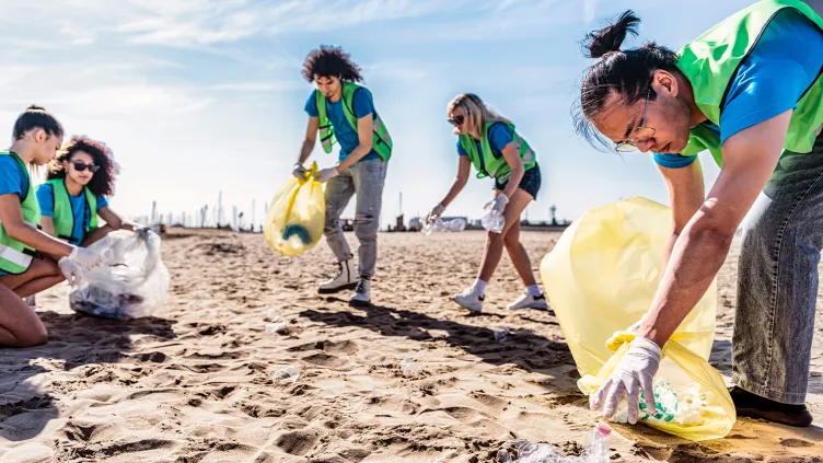 Group of eco volunteers picking up plastic trash on the beach