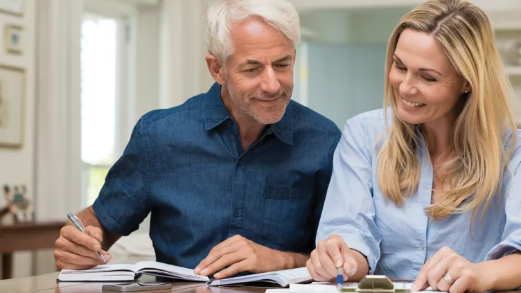 A mature couple reviewing documents and making notes together at a table